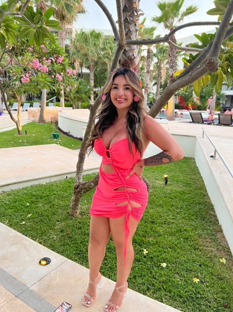 woman in pink dress standing in front of tree