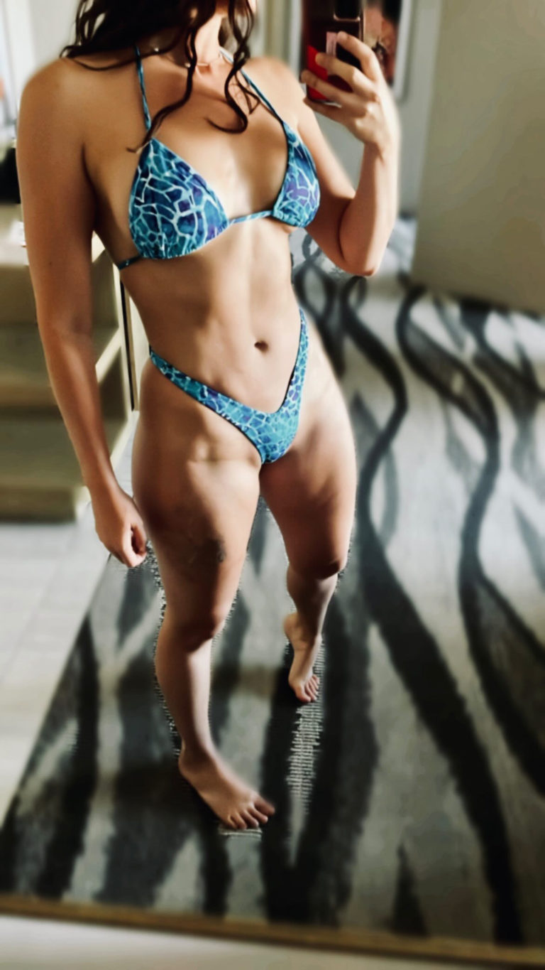 close up photo of woman in blue bathing suit in front of mirror