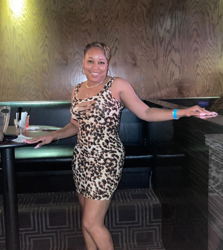 photo of woman in animal print dress standing in front of booth