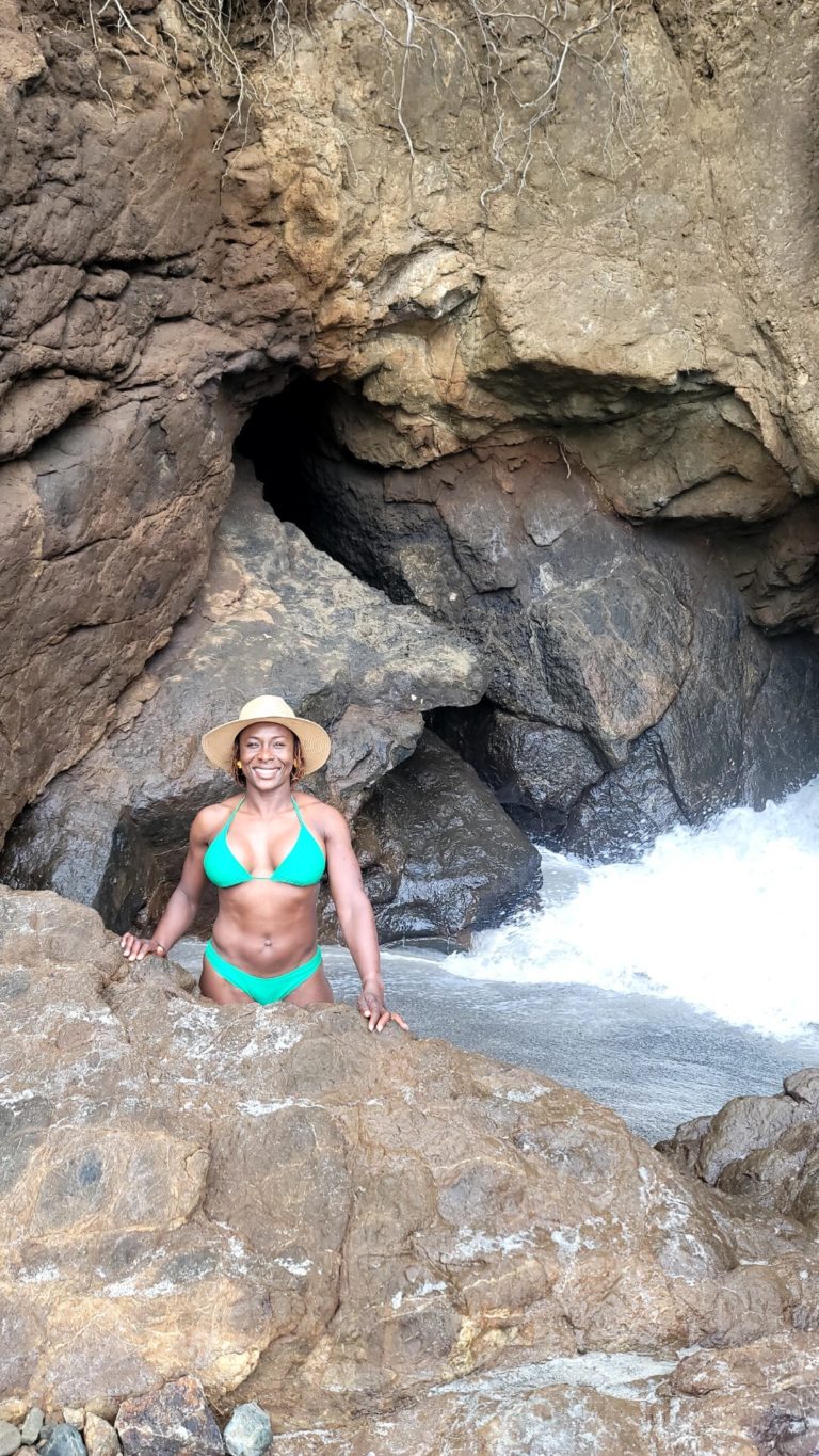 woman standing in water next to waterfall