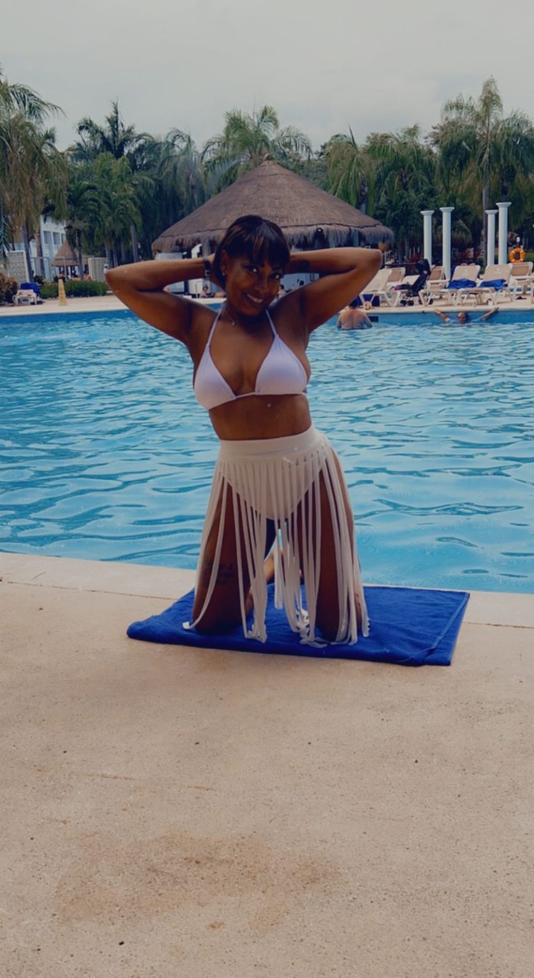 woman in white ensemble posing in front of pool