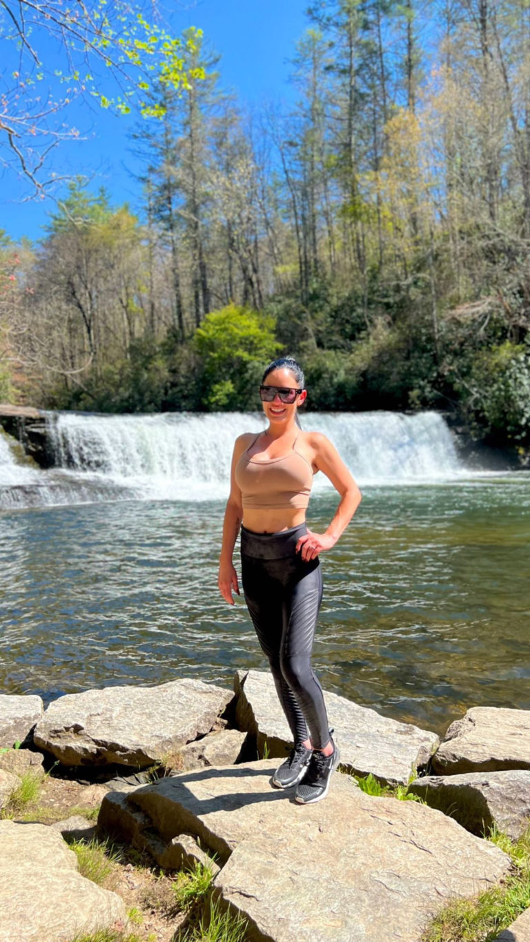 mujer en polainas posando frente a la cascada