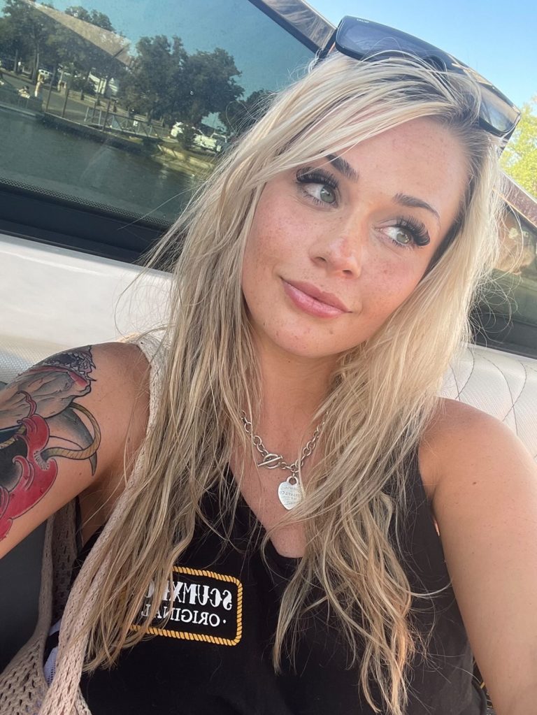 mujer rubia con camisa negra posando para selfie