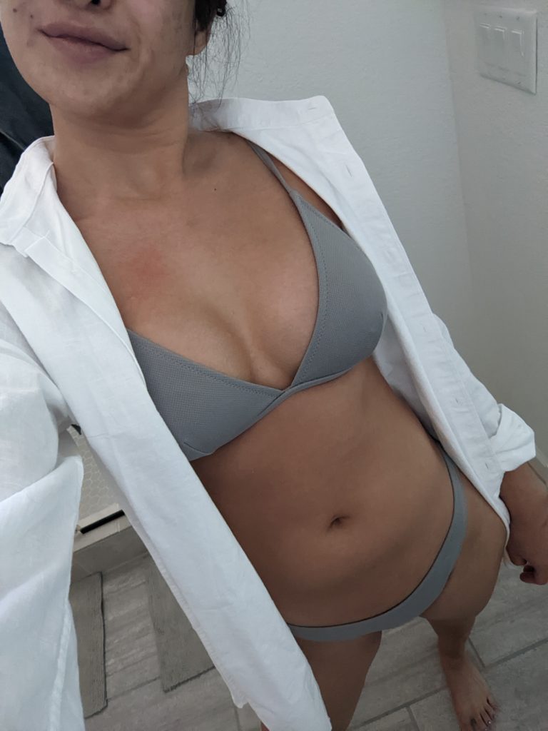 woman in grey bathing suit and white shirt posing for close up selfie
