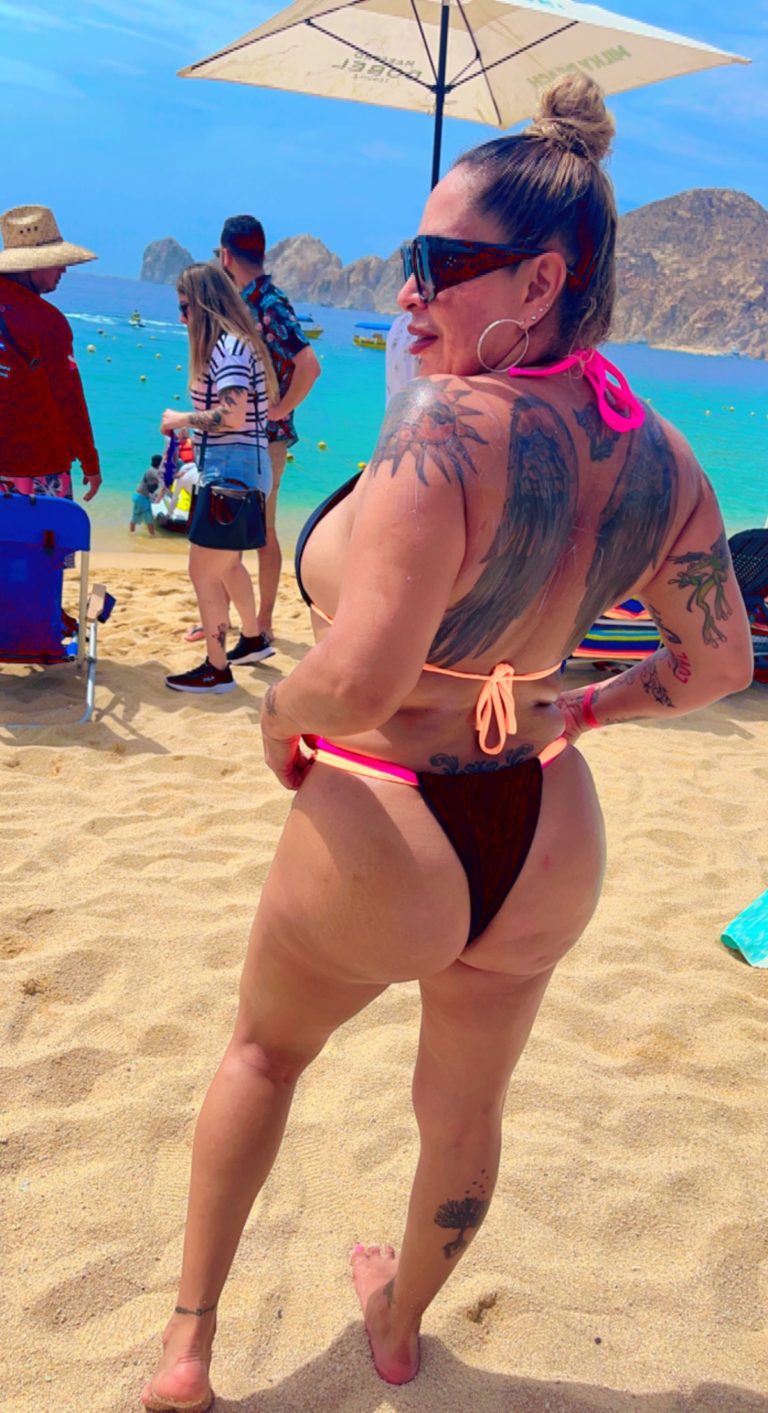 woman in black and pink bikini looking out at beach