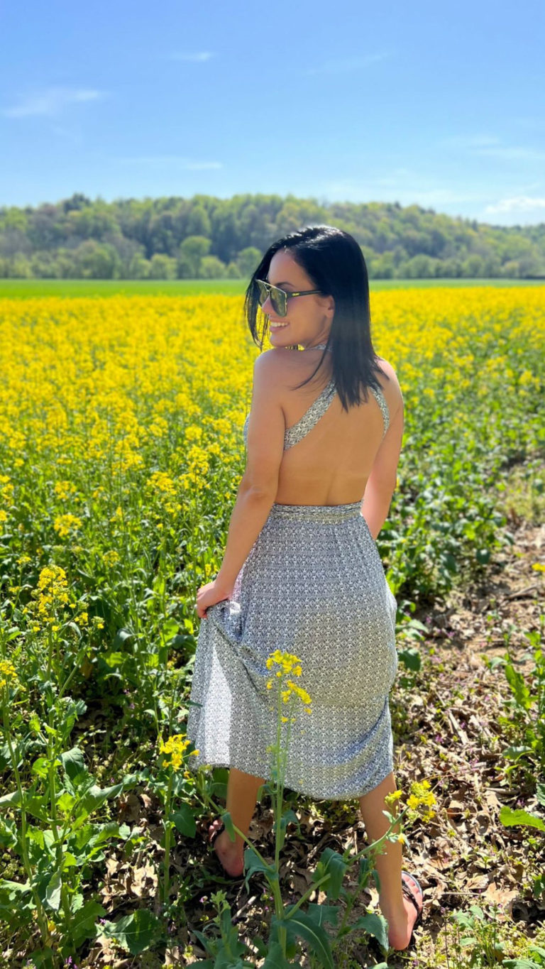 picture of woman in patterned dress in front of field of flowers