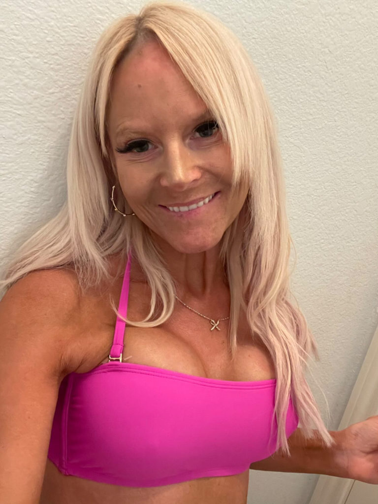 woman in pink top smiling in front of white wall