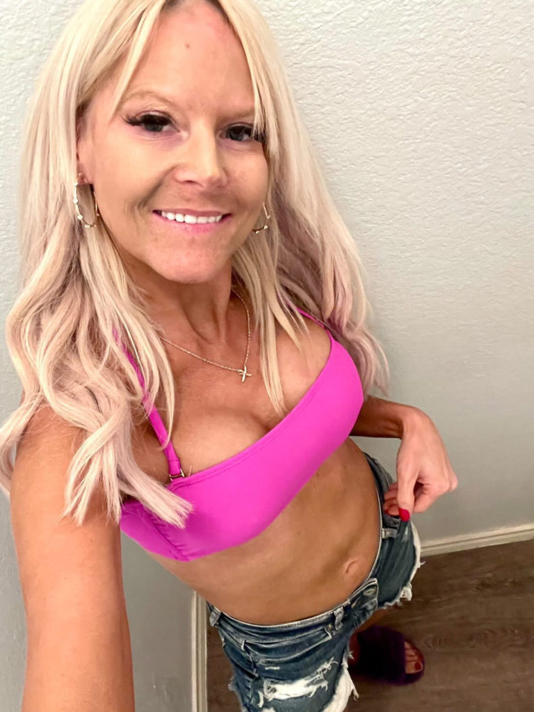 woman in pink top and jean shorts smiling for photo