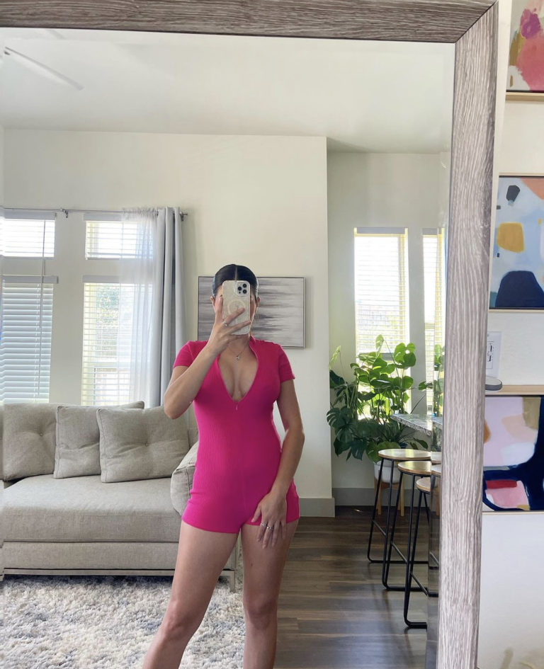 woman in pink outfit standing in front of mirror